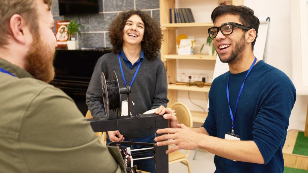 Three teachers talking around projector equipment while prepping for a an event presentation.