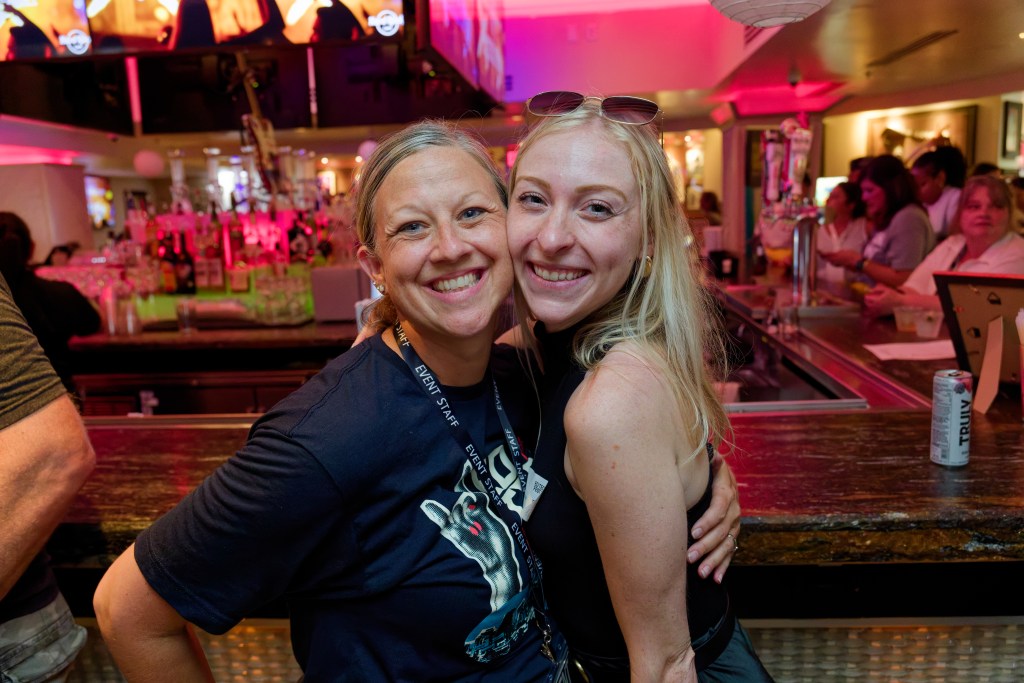 Two women hugging and smiling for a photo at a networking event