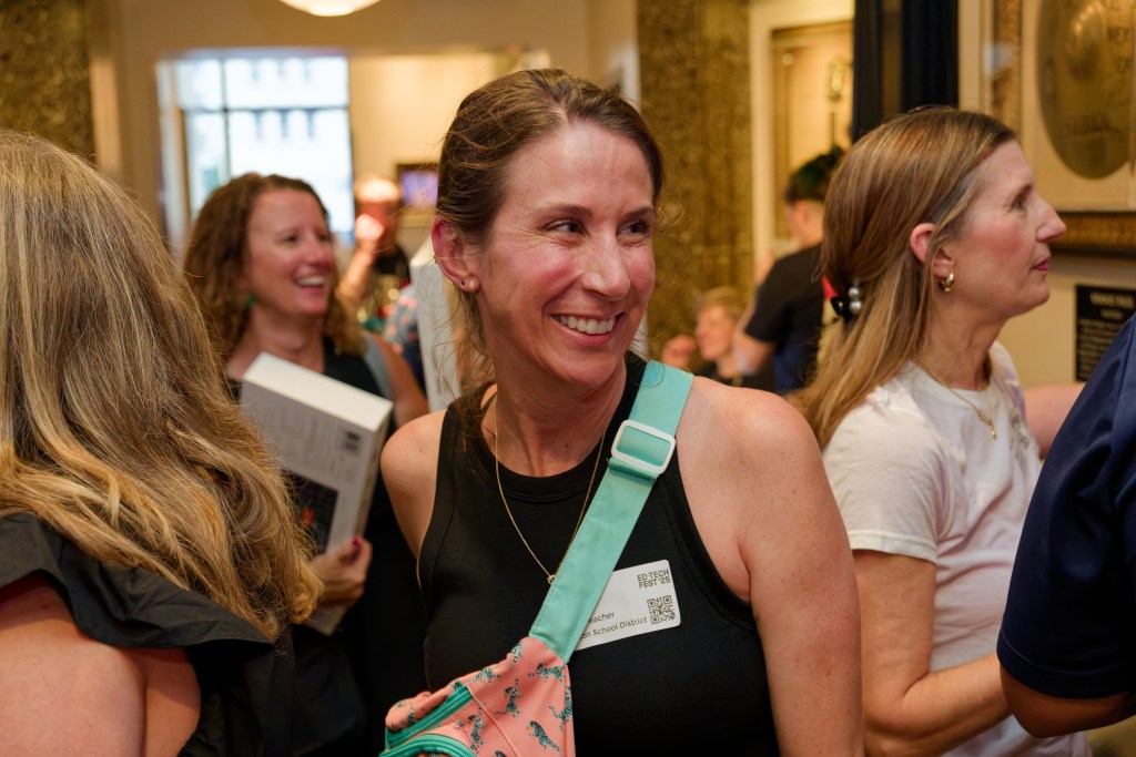 Candid shot of a woman smiling in front a crowded room of happy people